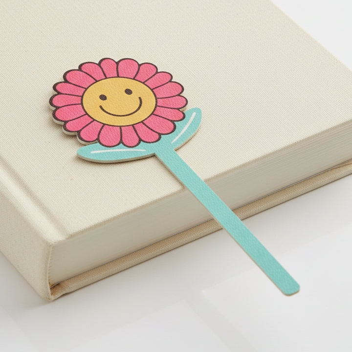 Good Vibes smiley flower bookmark on closed cream book grey background