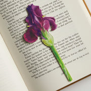 Painted purple iris flower bookmark lying on open book page