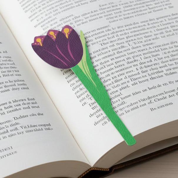 Purple tulip flower bookmark on open book on wooden surface