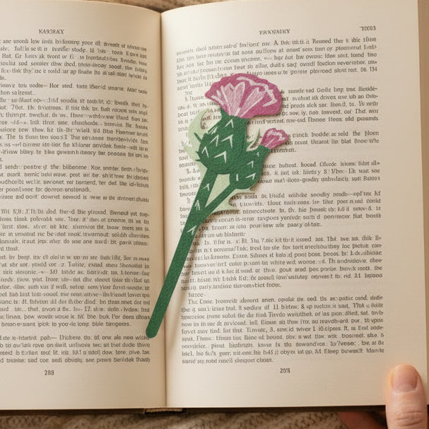 Scottish thistle flower bookmark on open book held in hand