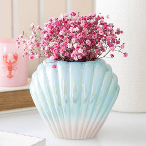 Iridescent clam shell vase with pink flowers on shelf