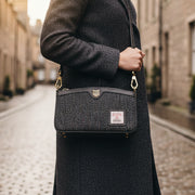 Ailsa black grey herringbone Harris Tweed purse held on Scottish street