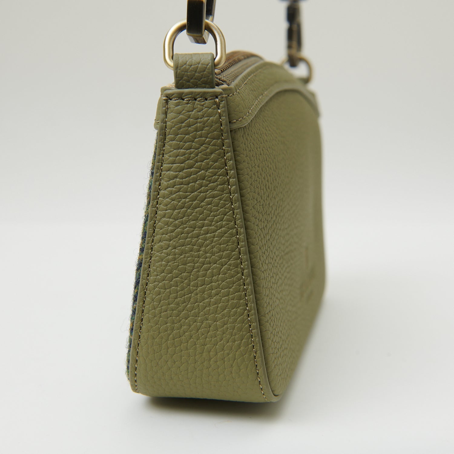 Close-up of Islander clasp and Harris Tweed label on green herringbone purse