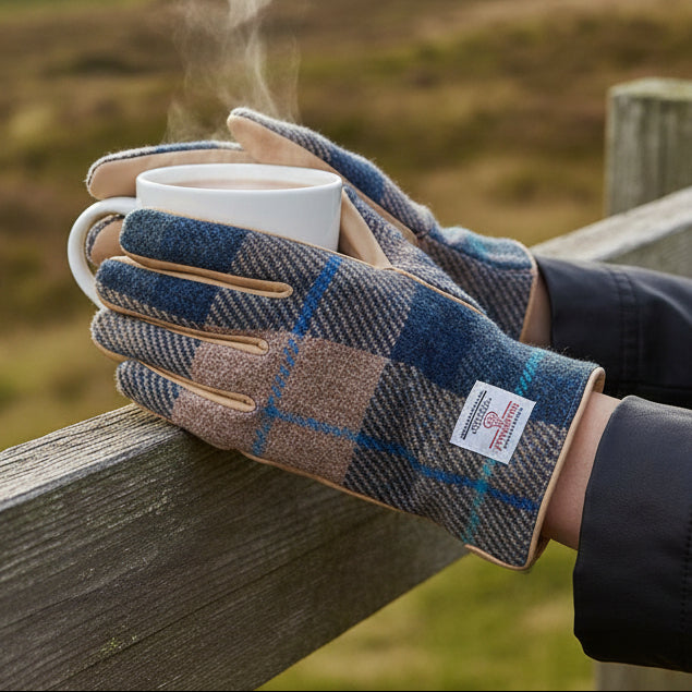 Navy beige tartan Harris Tweed gloves holding steaming mug on wooden fence outdoors