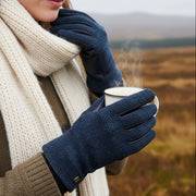 Navy herringbone Harris Tweed gloves worn holding enamel mug on Scottish moorland