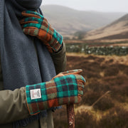Harris Tweed gloves in orange and blue tartan worn outdoors in Scottish highlands