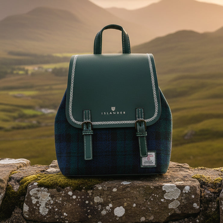Harris Tweed Black Watch backpack on stone wall with Scottish highland mountains