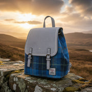 Harris Tweed blue tartan backpack on stone wall with Scottish highland sunset