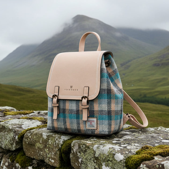 Harris Tweed Islander tartan backpack on mossy stone wall with misty mountain