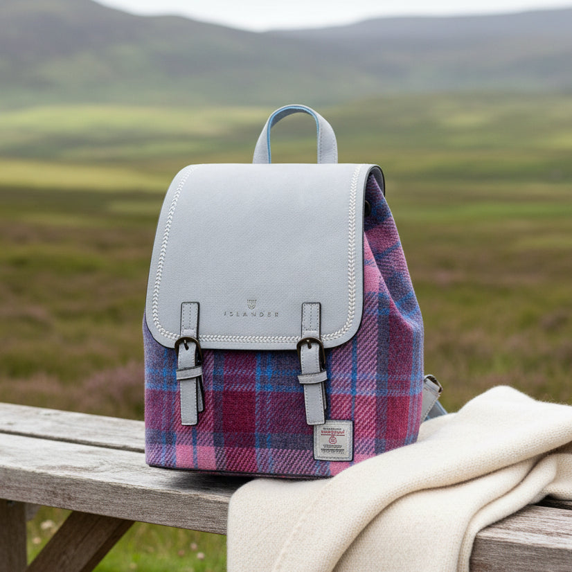 Harris Tweed pink and blue tartan backpack on wooden bench with highland view