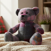 Lambswool teddy in pink and blue tartan on cream throw lifestyle shot.