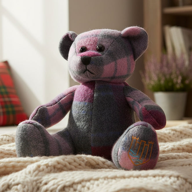 Lambswool teddy in pink and blue tartan on cream throw lifestyle shot.