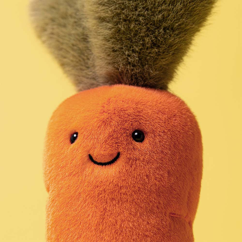 Close-up of Jellycat Carrot smiley face on yellow background