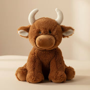 Extra large brown Highland cow soft toy sitting on beige background