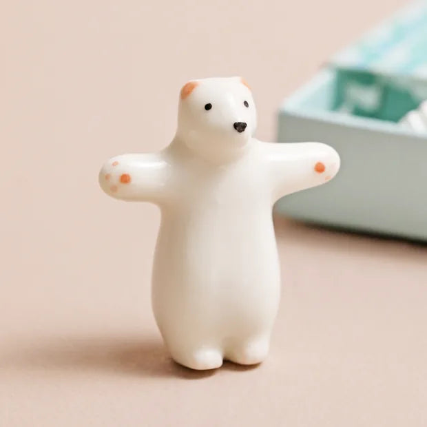 Close-up of ceramic bear with pink paws and outstretched arms