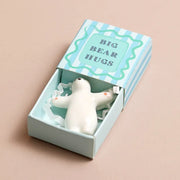 White ceramic bear token with open arms in blue striped matchbox