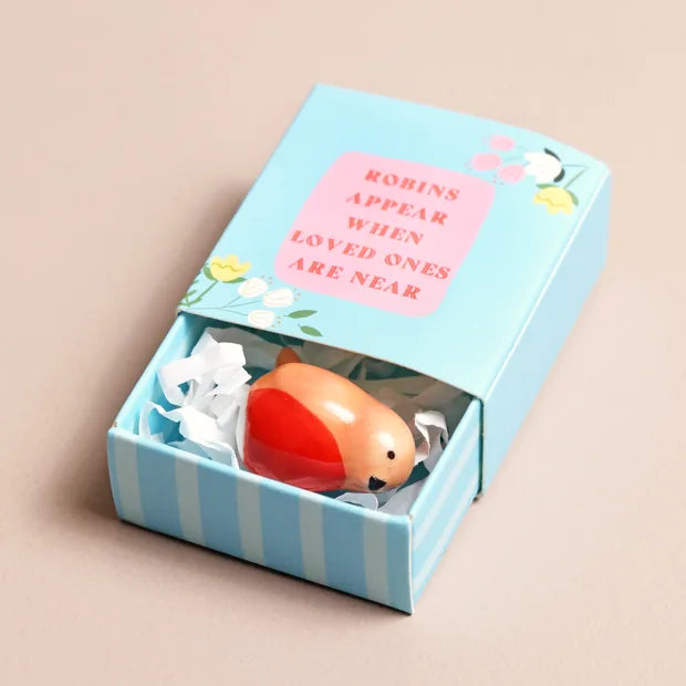 Tiny ceramic robin in blue matchbox on pink surface