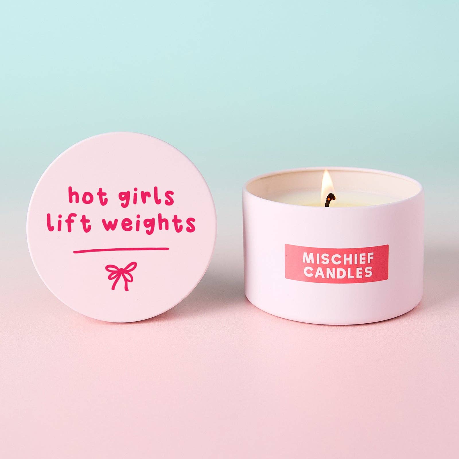 Hot Girls Lift Weights lid propped beside burning pink tin candle