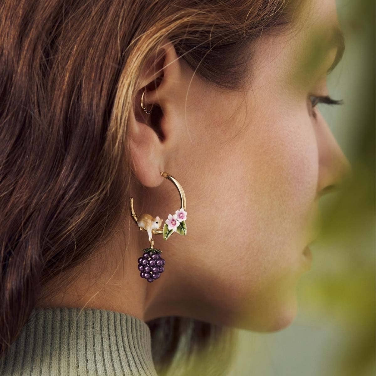 Model wearing Bill Skinner Blackberry & Mouse Hoop Earrings featuring hand-painted enamel flowers, gold hoop, and blackberry charm.