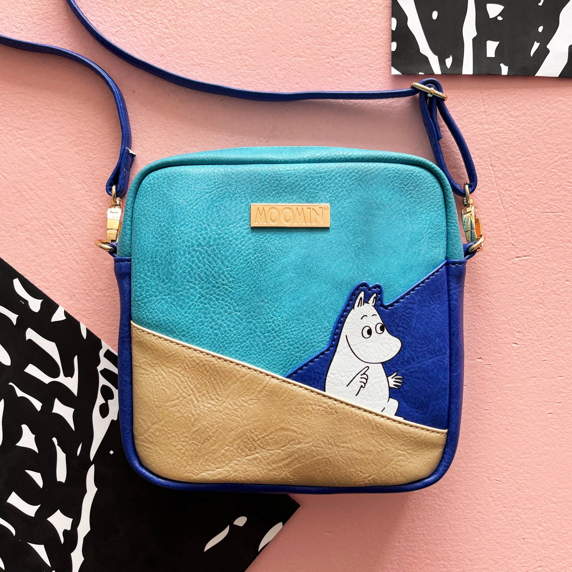 Moomin Gold Mini Bag flat lay showing front design with Moomin motif and gold logo plate.
