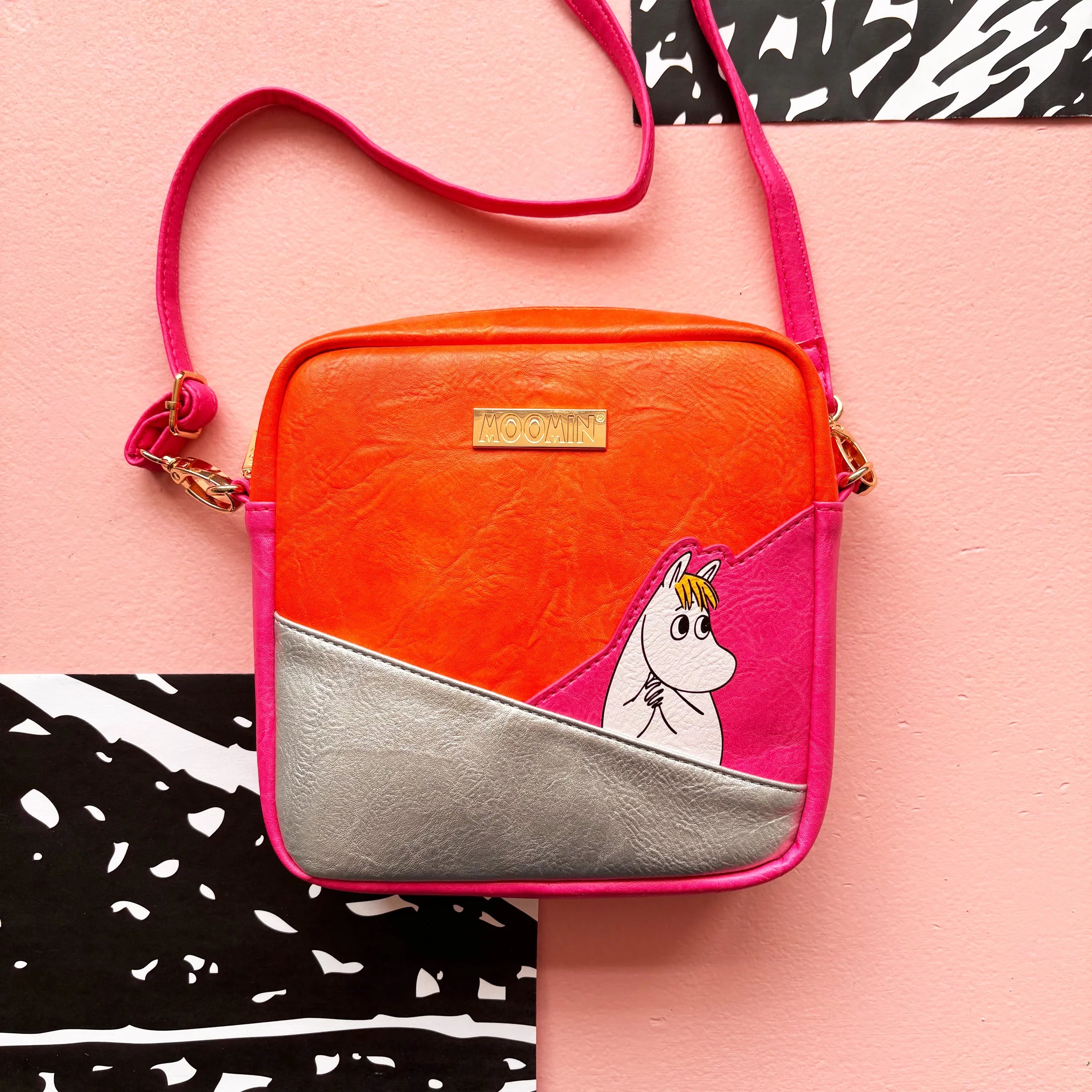 Colour block Moomin Snorkmaiden Mini Bag with gold zip and detachable strap on pink background.