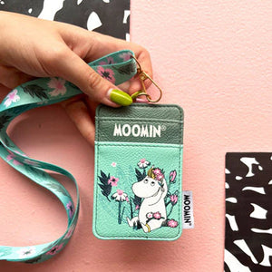 Hand holding Moomin Snorkmaiden Lanyard with floral print and mint green tones on pink background.
