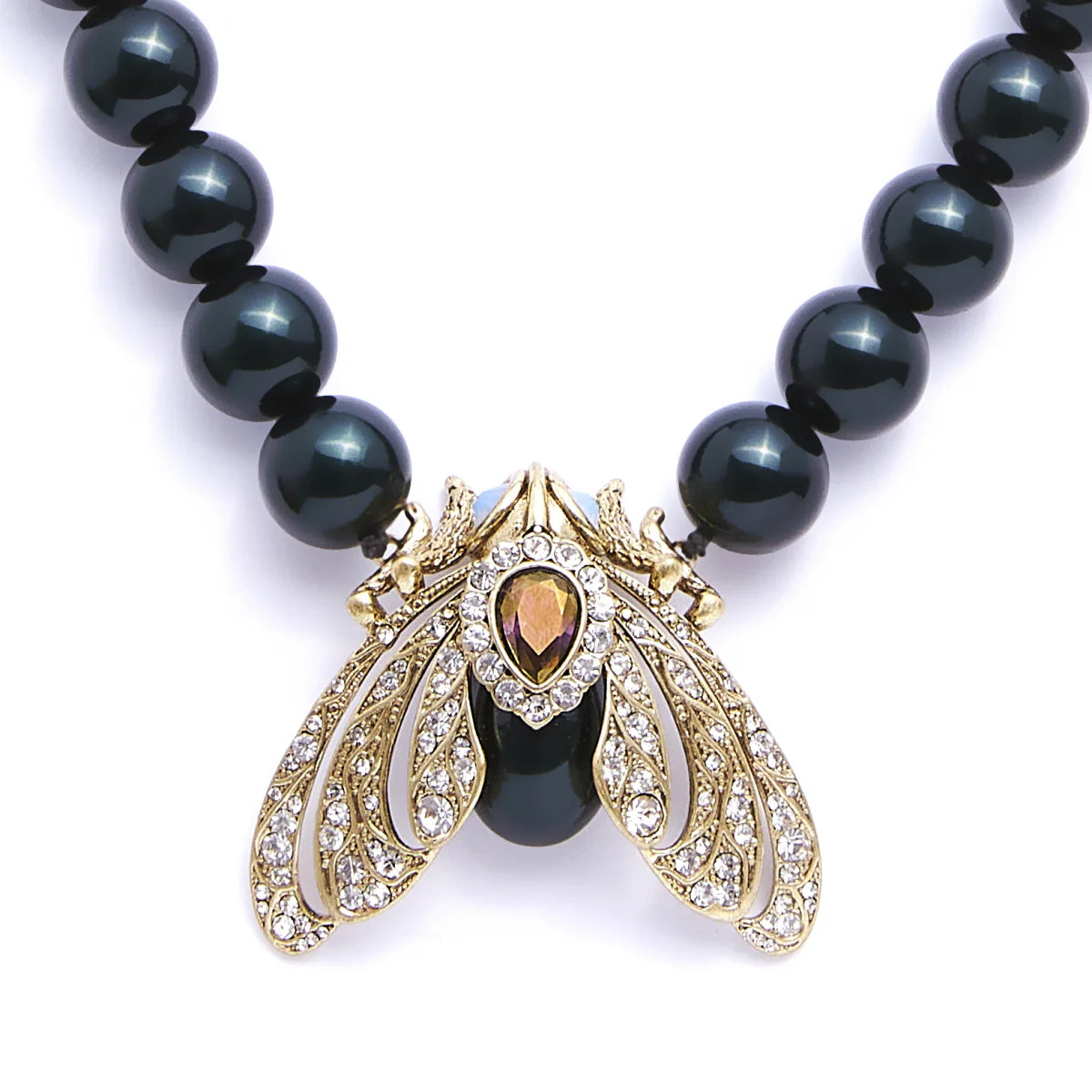 Close-up of Bill Skinner Moth Statement Necklace featuring a gold moth pendant adorned with crystals and Tahitian pearls on a white background.
