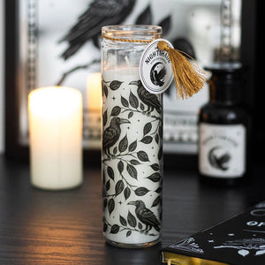 Mystic Raven Deadly Nightshade Candle on a dark table with gothic décor in the background.