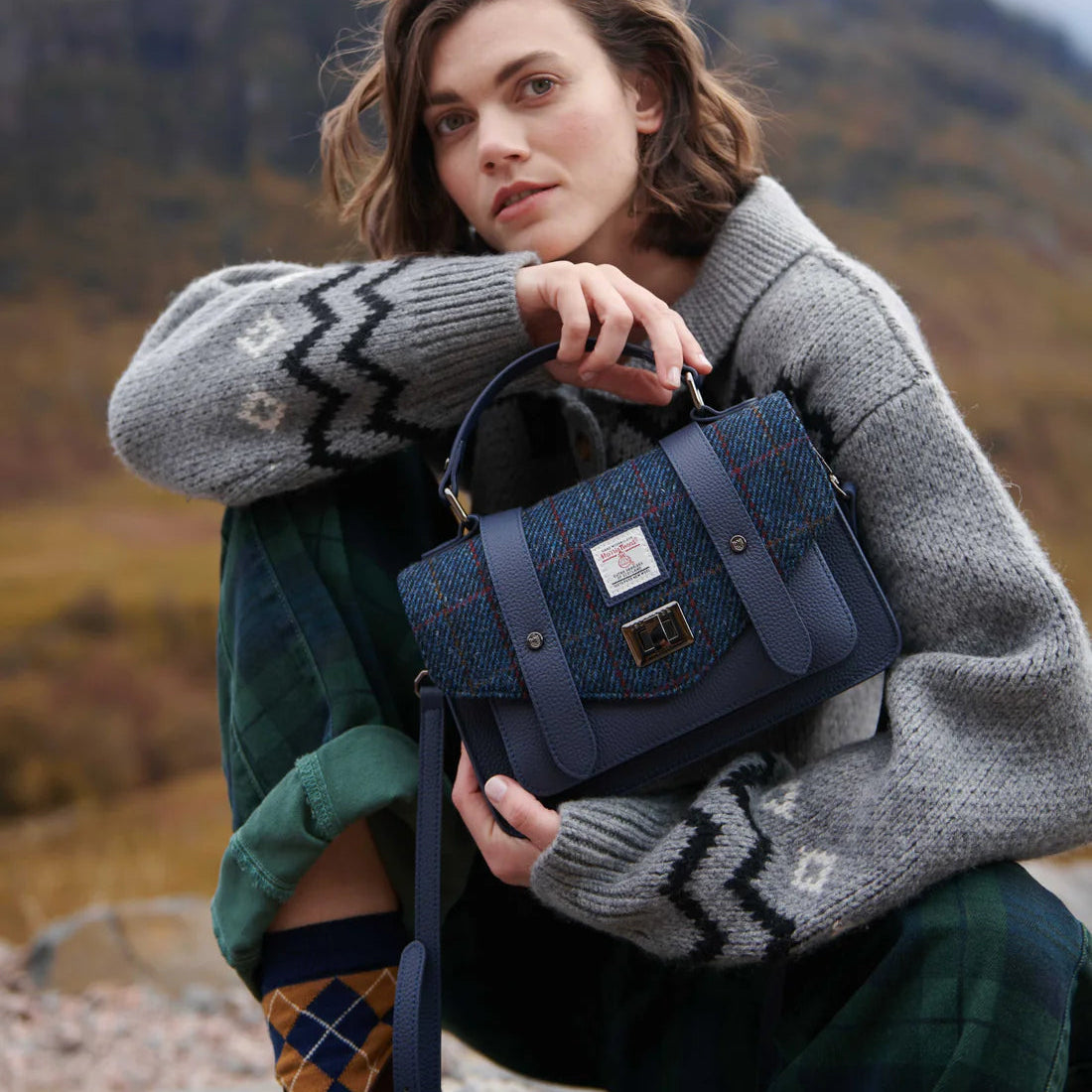 Lifestyle image of navy Harris Tweed leather satchel worn outdoors in the Scottish Highlands.