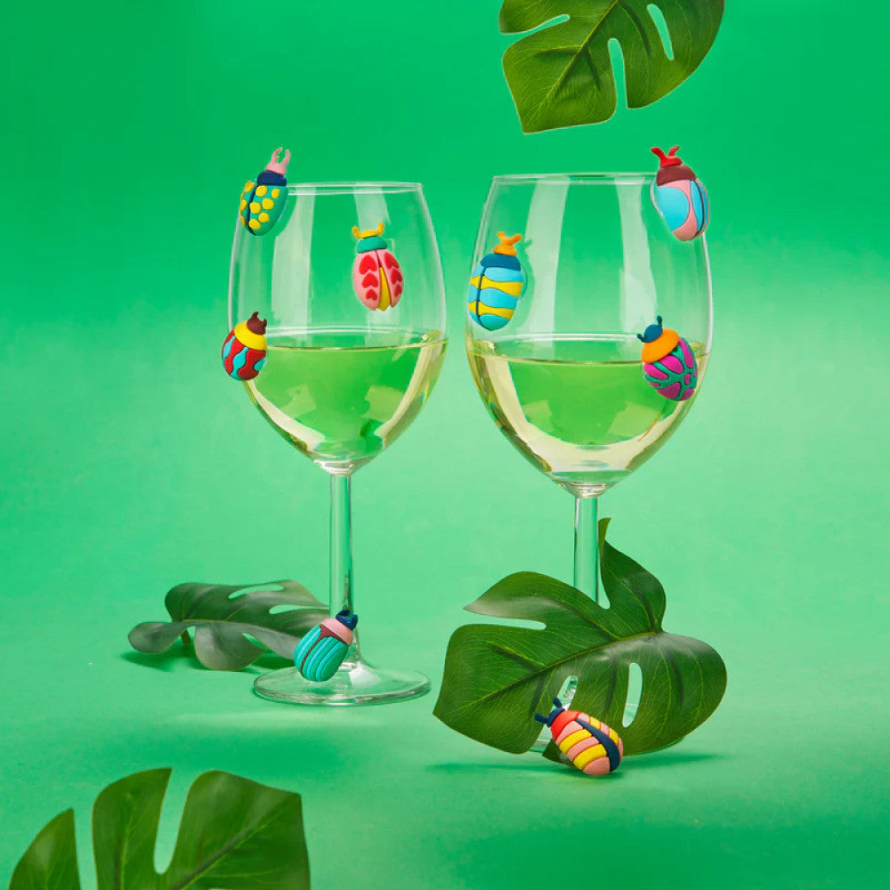 Two wine glasses with beetle markers on green background with plants