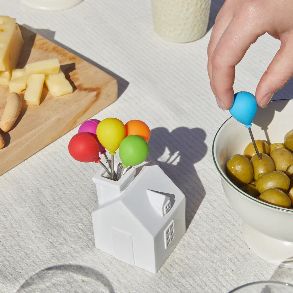 Hand picking fork from ceramic balloon house stand on table with cheese
