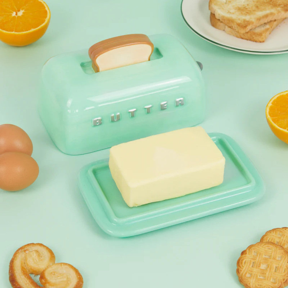 Toaster butter dish open with butter inside on green background