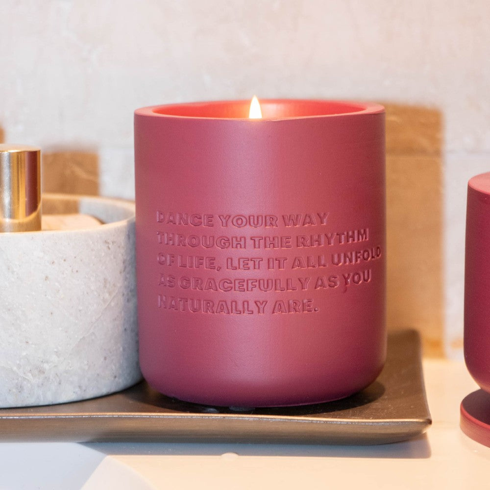 Lit burgundy cement candle on tray in warm lifestyle setting