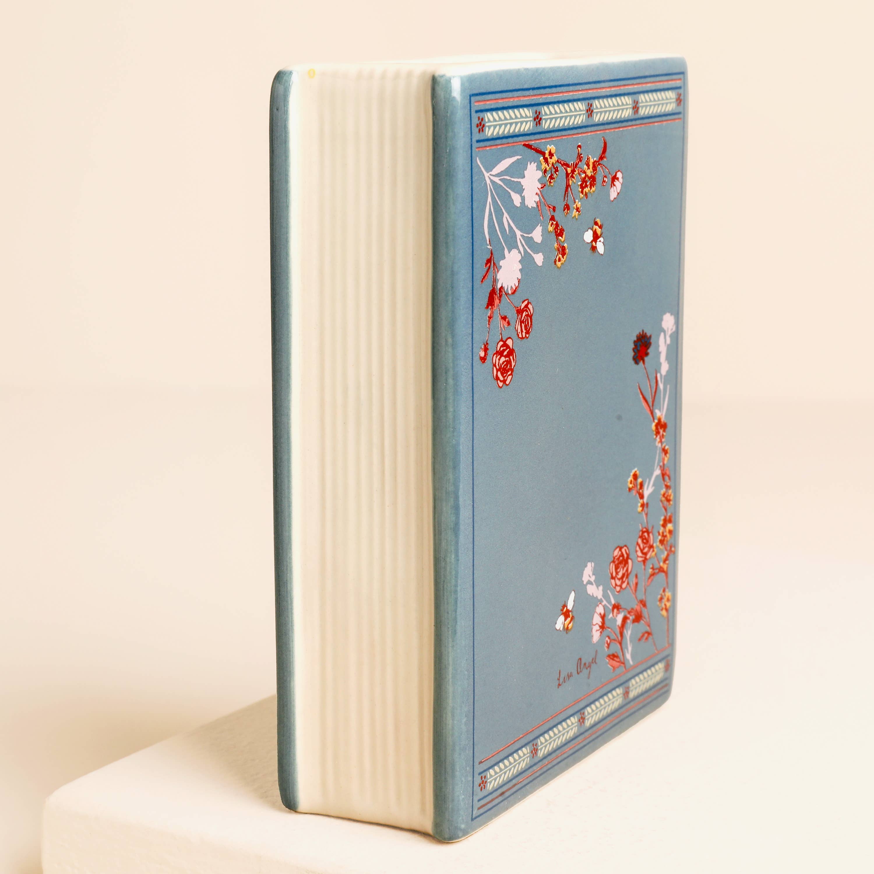 Side view of ceramic book vase showing realistic ridged page detailing.
