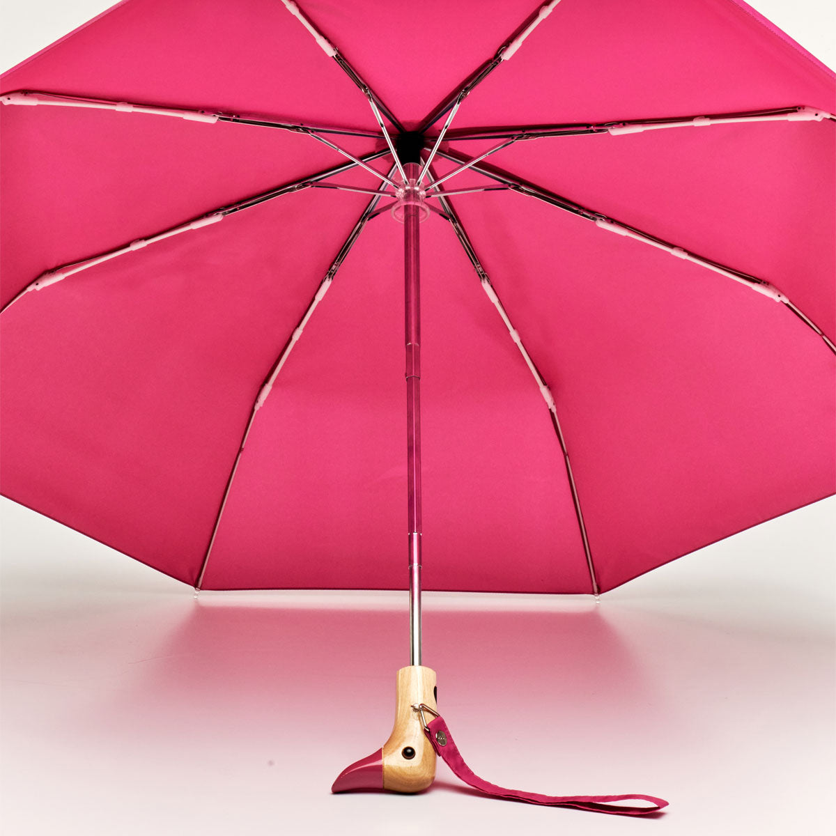 Pink duck umbrella open from underneath showing ribs and wooden handle