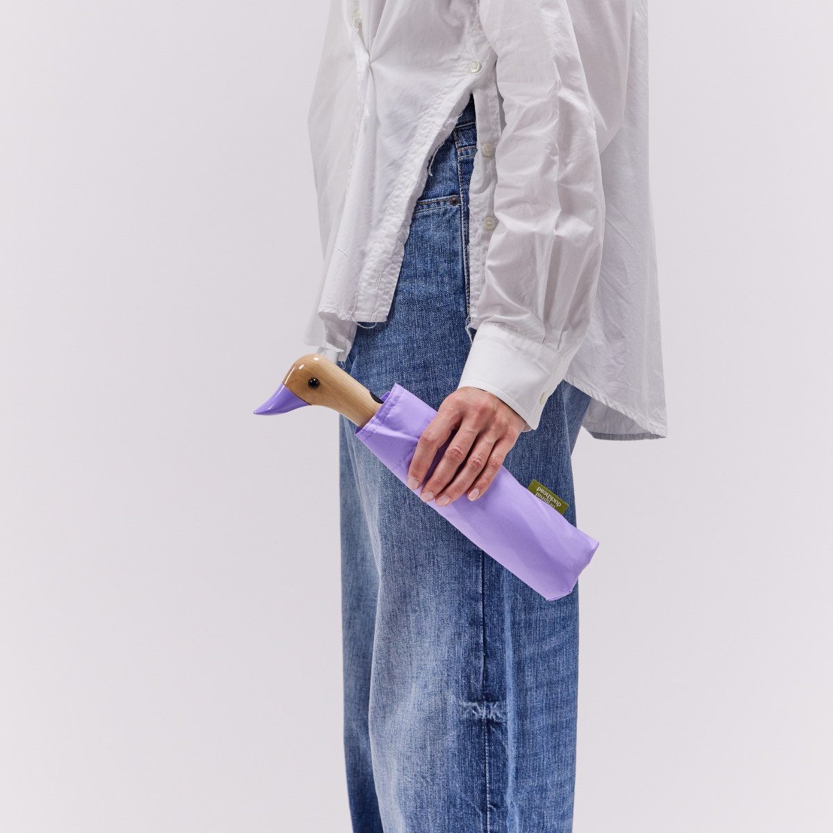 Closed lilac compact duck umbrella held in hand lifestyle shot