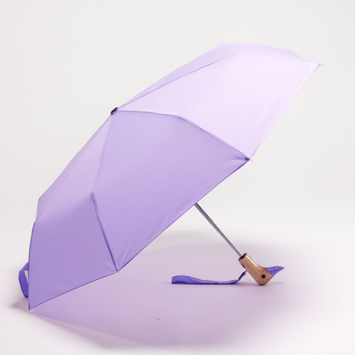 Macaron lilac compact duck umbrella open resting on light background