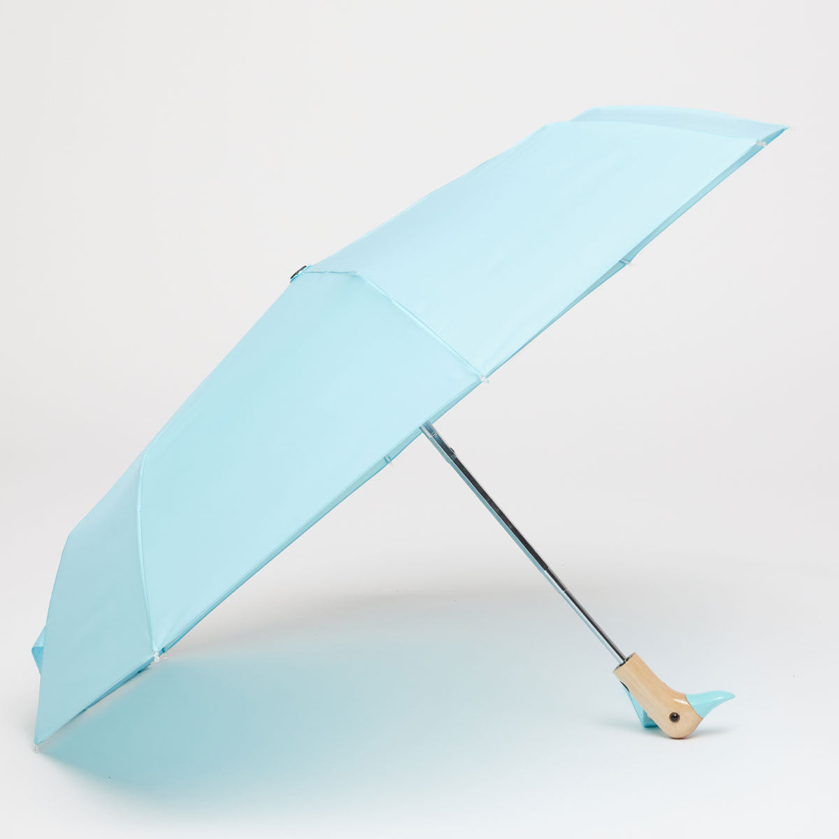 Popsicle blue compact duck umbrella open resting on light background