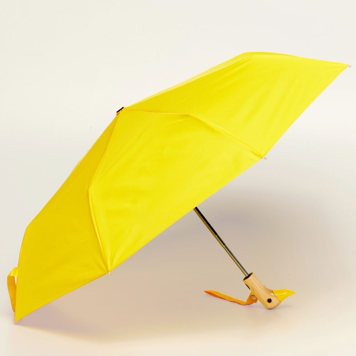 Yellow compact duck umbrella open side view on light background