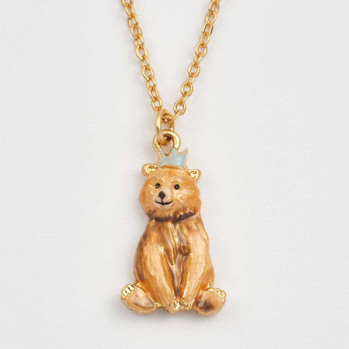 Close-up of Party Bear pendant with icy blue hat on gold chain.