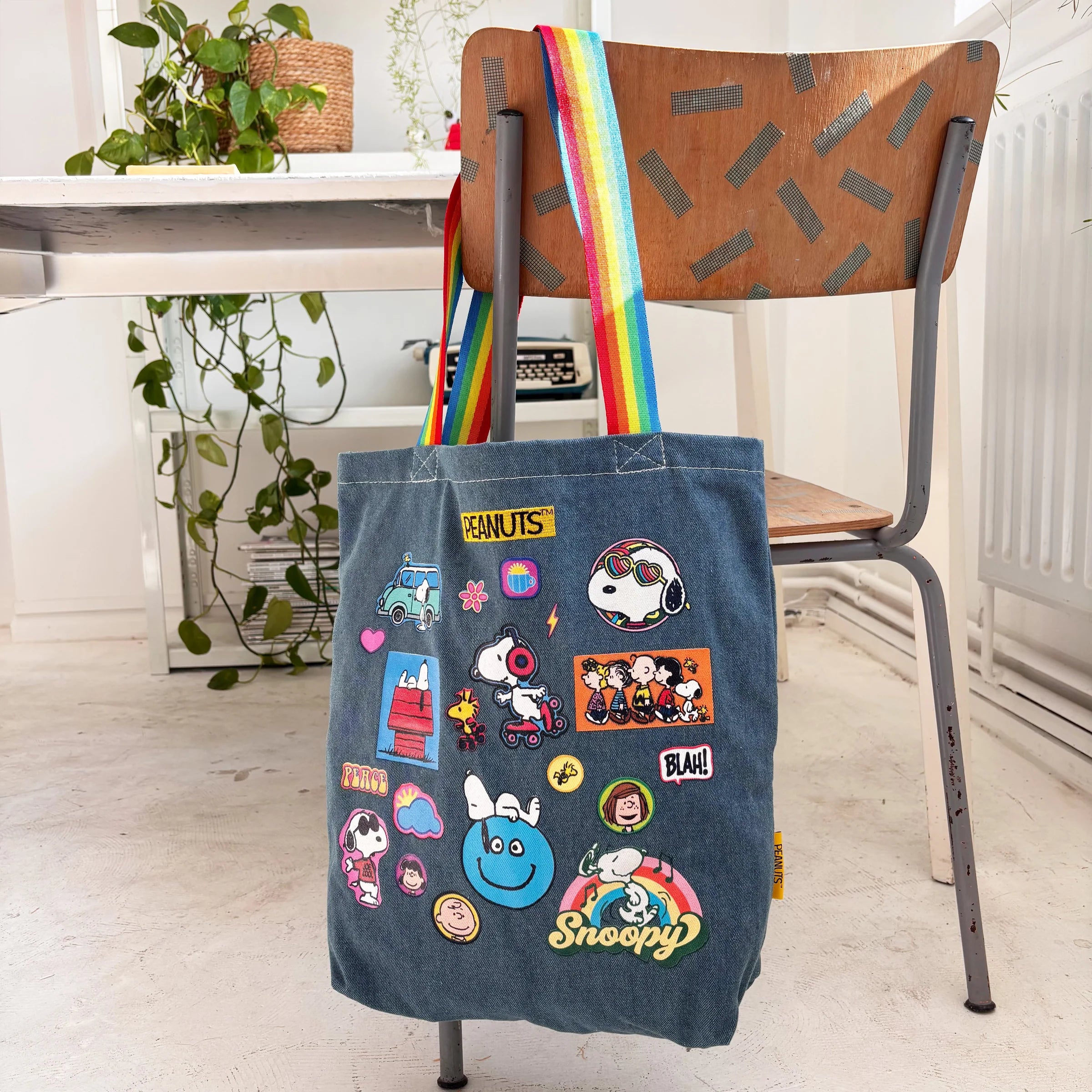 Peanuts patch denim tote bag with rainbow straps on chair