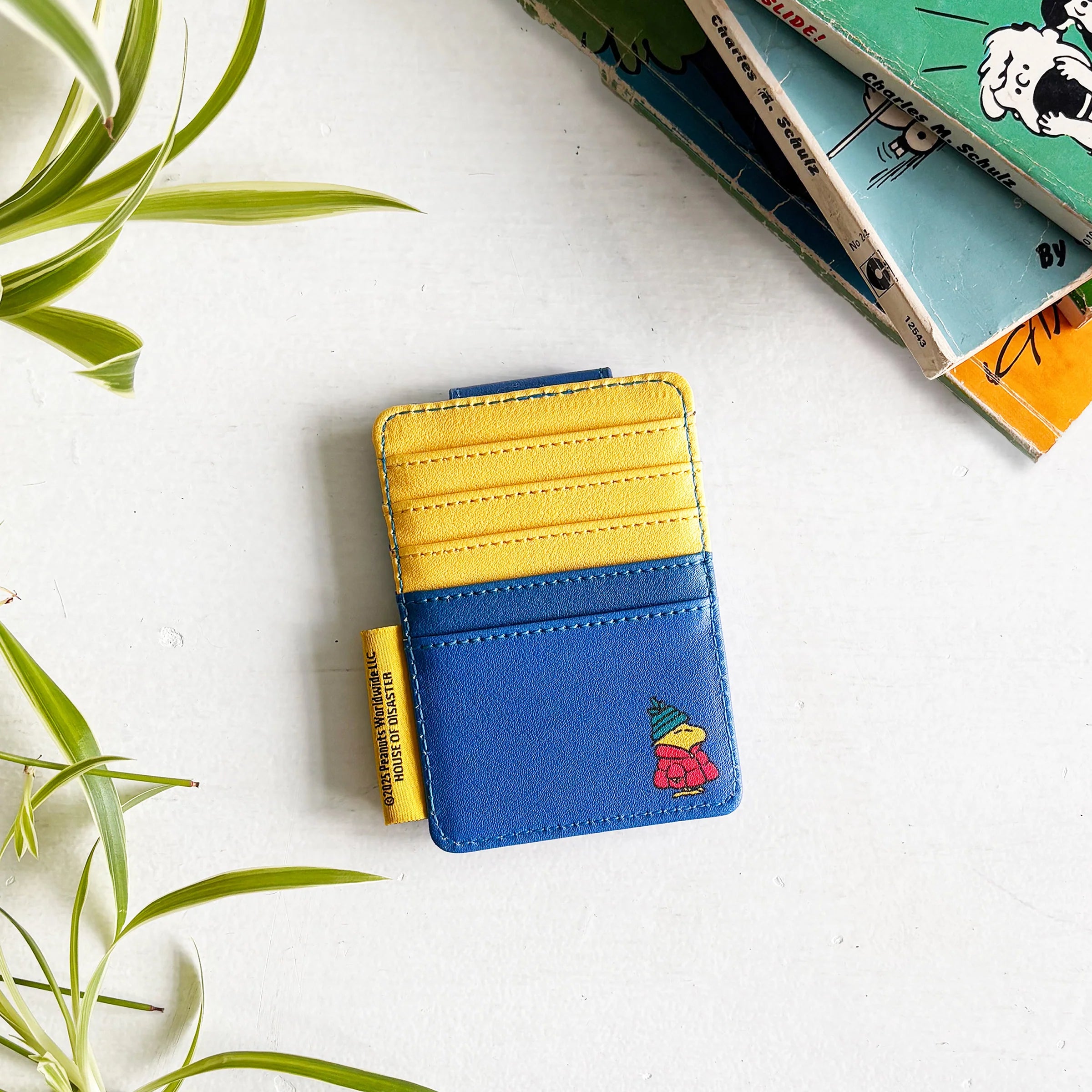 Back view of Peanuts Snoopy Coat Foldover Card Holder showing yellow and blue design with Woodstock illustration and Peanuts tag.