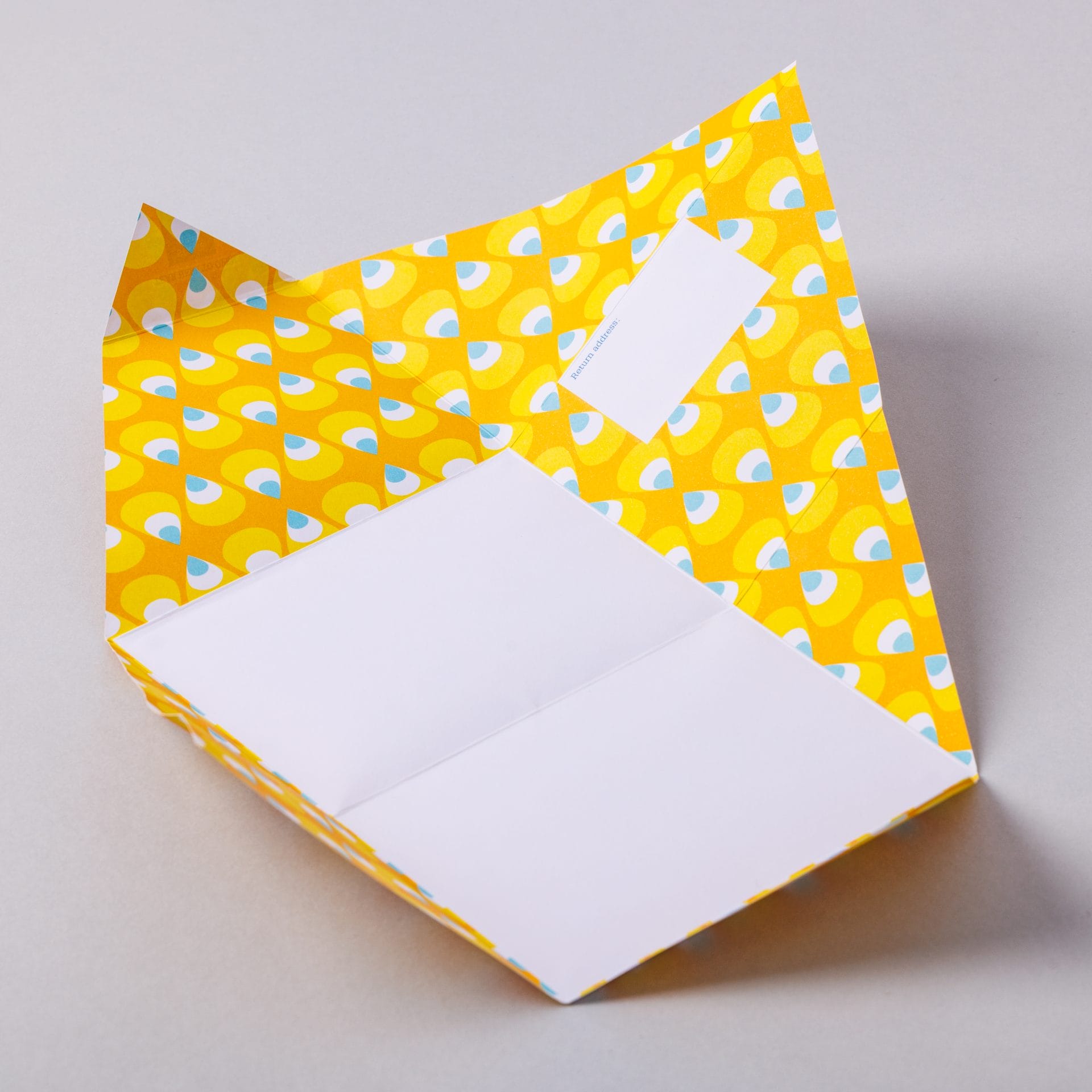 Unfolded Pencil Pigeon with yellow and blue geometric interior on grey background