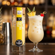 Piña Colada cocktail mix in a clear glass tube with cork lid, showing pineapple and coconut pieces.