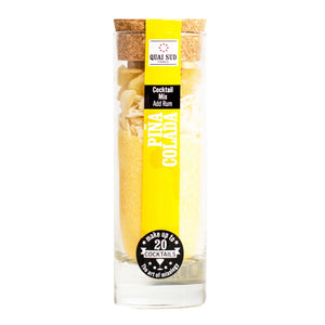 Piña Colada cocktail mix in a clear glass tube with cork lid, showing pineapple and coconut pieces.