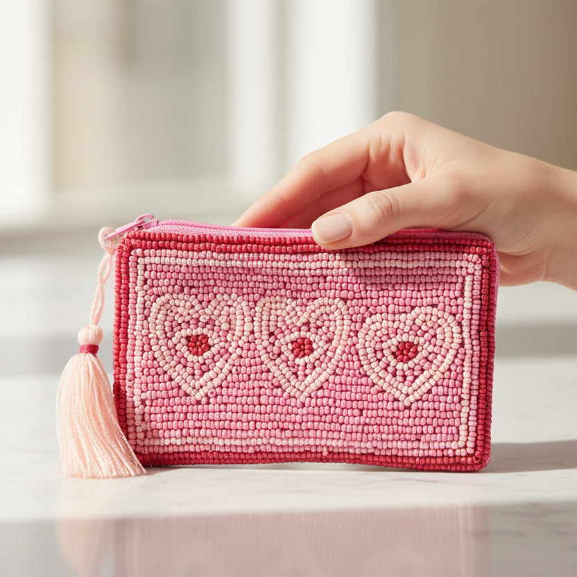 Beaded heart coin purse held in hand showing pink and red seed bead design