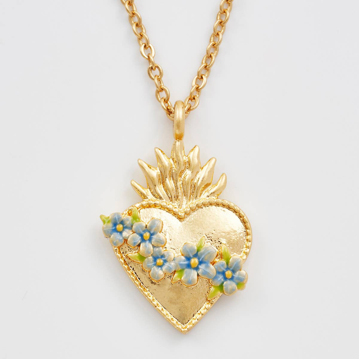 Gold sacred heart necklace with blue floral pendant on white background.