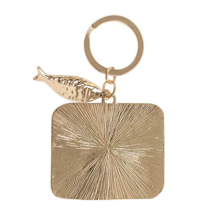 Gold keyring back with decorative fish charm on white background