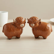 Highland cow salt and pepper shakers facing each other on wooden table