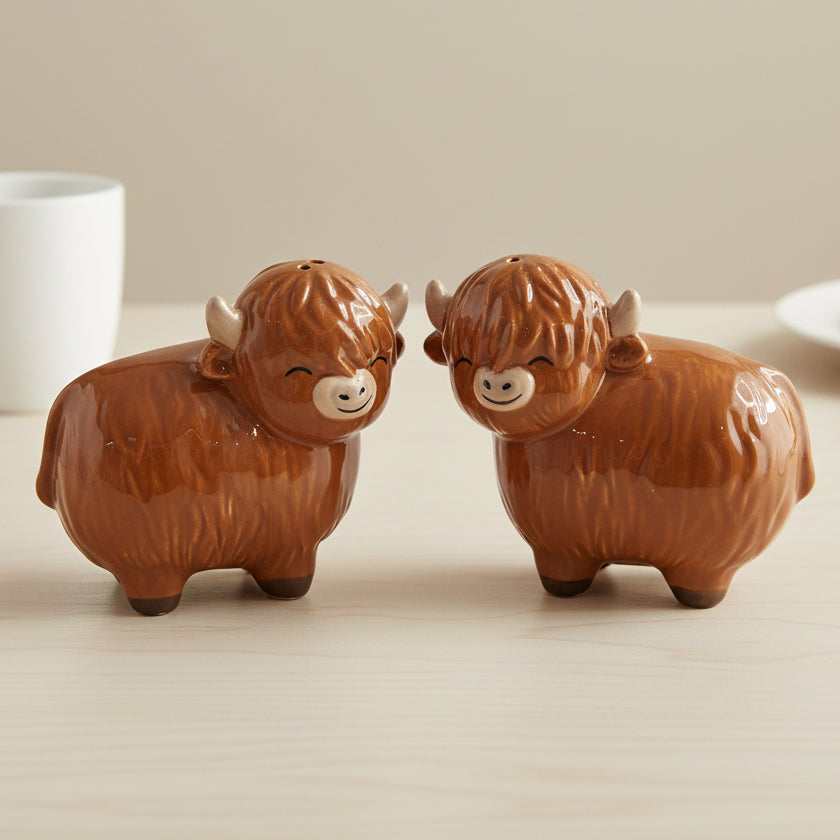 Highland cow salt and pepper shakers facing each other on wooden table